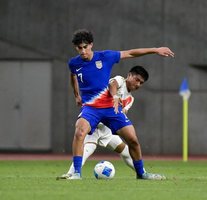 Aiden Hezarkhani shielding the ball in a USA youth national team kit